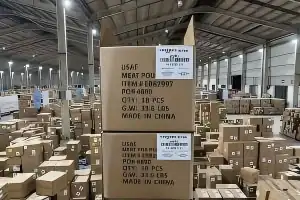 Stacked cartons in a warehouse with printed shipping marks and a white identification label.